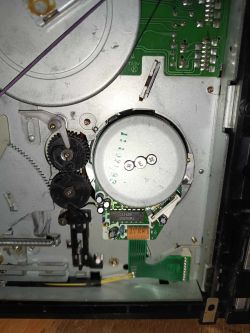 Wnętrze magnetowidu z widocznymi częściami mechanicznymi, kołami zębatymi i płytką drukowaną.