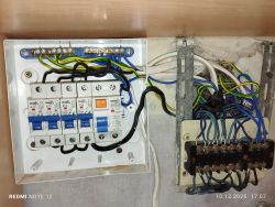 Rozdzielnica elektryczna z widocznym chaosem okablowania i starymi podzespołami