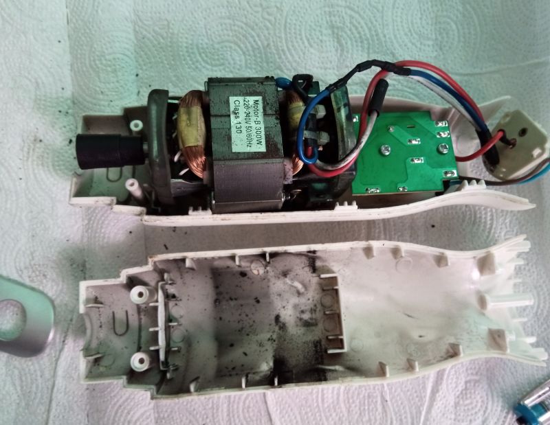 Rozebrana obudowa blendera pokazująca silnik szczotkowy i elektronikę na tle białego papieru.