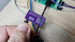 Close-up of a purple PCM5102 circuit board held in hand, connected to wires.