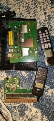 Dwie zielone płytki PCB oraz dwa telefony na niebiesko-białym dywanie