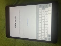 Tablet z ekranem blokady aktywacji i klawiaturą na zielonym tle.
