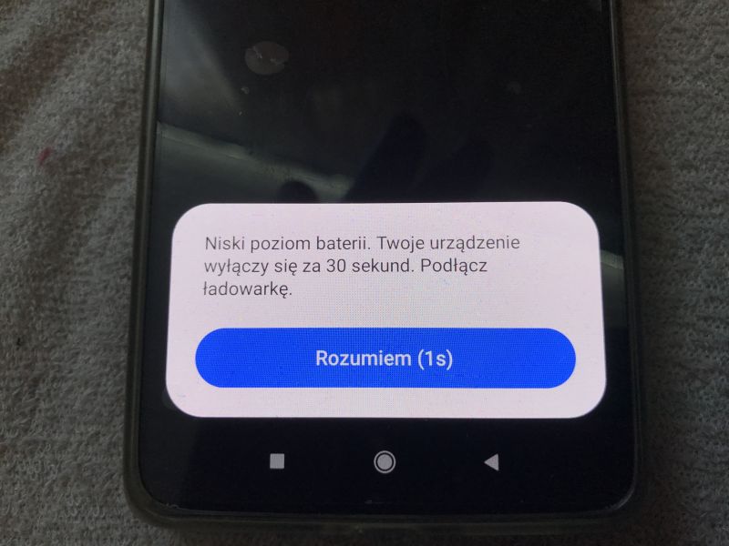 Komunikat na ekranie smartfona o niskim poziomie baterii i konieczności podłączenia ładowarki