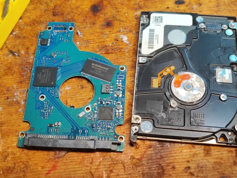 Interior and PCB of a Disassembled Hard Drive Disassembled HDD and its circuit board on a wooden table.
