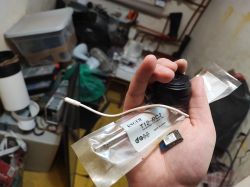 A hand holding a KSGER T12-BC2 soldering tip, a black electronic component, and a small electronic module.