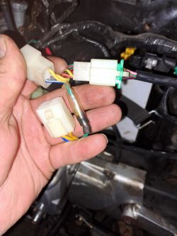 Ręce trzymające złącza elektryczne z kolorowymi przewodami w motorowerze Romet Ogar 202 Fi.