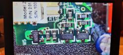 Obraz ukazuje zbliżenie mikroskopowe płytki drukowanej z komponentami elektronicznymi.