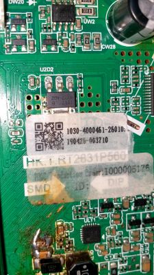Close-up of a green circuit board with SMD parts and a label with a QR code and printed numbers