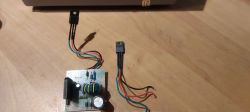 Płytka obwodu elektronicznego z przymocowanymi kondensatorami i kolorowymi przewodami.