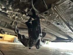 Black part hanging on wires beneath a car.