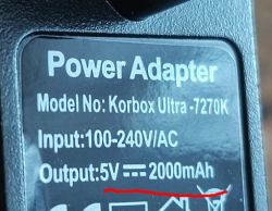 Zbliżenie na etykietę zasilacza z modelem Korbox Ultra-7270K, wyjście 5V 2000mAh.
