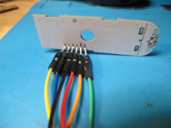White PCB TH01 with connected wires and an LED on a blue mat.