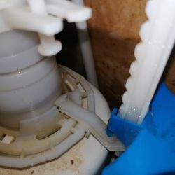 Close-up of a toilet float mechanism with a plastic lever and gear.