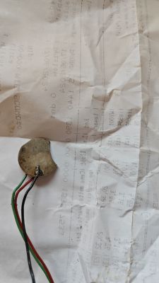 Uszkodzony czujnik piezoelektryczny z odłączonymi przewodami leży na kartce papieru.