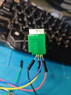 PCB with Colored Wires Green PCB with attached colored wires against a keyboard background.