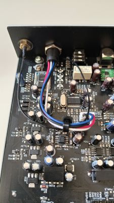 Zbliżenie na wnętrze amplitunera JRK Audio Evothon, ukazujące płytę PCB z elektroniką, zmontowanymi kondensatorami, układami scalonymi i przewodami.