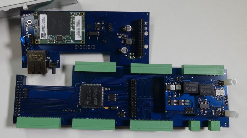 Niebieska płytka PCB z układami scalonymi, złączami zielonymi i gniazdem Ethernet na białym tle