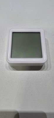Square device with a dark LCD screen and white frame on a light surface.