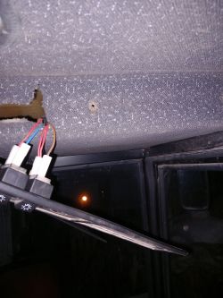 Wnętrze pojazdu z widocznymi przełącznikami i otworem w podsufitce.