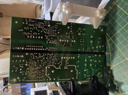 Spód zielonej płytki PCB z wieloma lutami, na macie pomiarowej z podziałką.