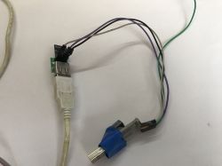 Prototype electronic circuit with wires and USB and PS/2 connectors on a white background.