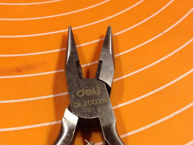 Metalowe szczypce na pomarańczowej podkładce