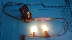 Akumulator elektronarzędzia z testerem USB i dwiema świecącymi żarówkami na niebieskiej macie