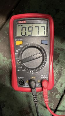 Cyfrowy miernik napięcia UNI-T UT33B wskazujący wartość 0.977 V.