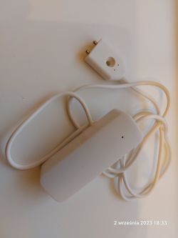 White sensor with a cord and plug on a light background.