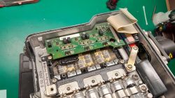 Otwarty moduł elektroniczny z płytką PCB i odsłoniętymi szynami mocy na zielonym stole