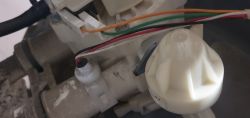 Zbliżenie na przewody elektryczne i plastikowe elementy wewnętrzne urządzenia, prawdopodobnie zmiękczacza wody.