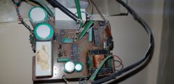 Stary domofon - widok od strony druku Widok wnętrza starego domofonu z widocznymi elementami elektronicznymi, takimi jak kondensatory i transformator.