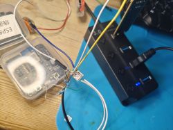 An electronic board connected to a USB hub with multiple wires on a workbench.