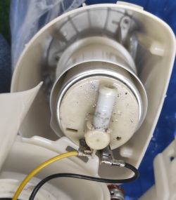 Zbliżenie na starą pompę paliwa z przewodami w plastikowej obudowie