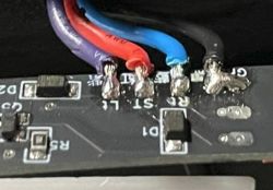 Płytka modułu z przewodami lutowanymi do złącz Zbliżenie płytki PCB z przylutowanymi przewodami: fioletowym, czerwonym, niebieskim i czarnym