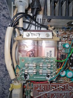 Widok wnętrza urządzenia elektronicznego z widocznymi przewodami i komponentami.