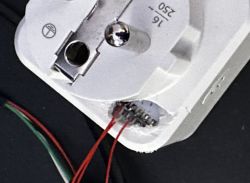 View of an electrical plug with exposed pin access and connected wires.