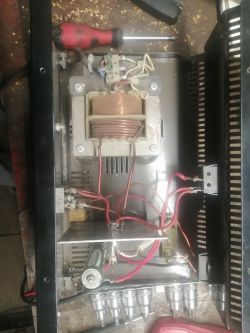 Wnętrze urządzenia elektronicznego z widocznymi kablami i cewką.