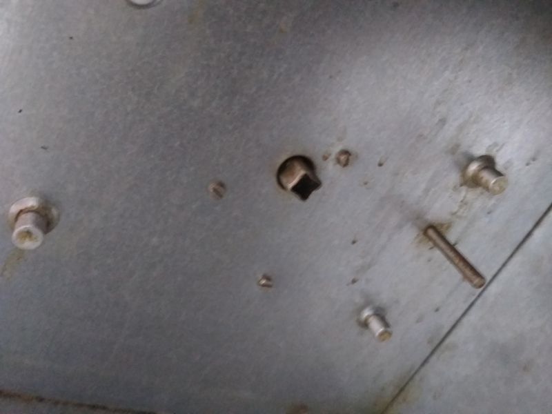Zbliżenie na metalową powierzchnię z kilkoma śrubami oraz wystającym metalowym trzpieniem, będącą częścią obudowy opiekacza Predom Selfa.