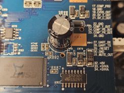 Zbliżenie na płytę drukowaną z widocznymi komponentami elektronicznymi, w tym kondensatorem elektrolitycznym i układem scalonym ST232C.