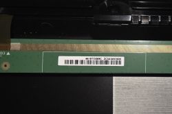 Close-up of a green RAM memory module seated in a slot, with a white barcode label.