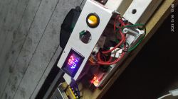 Panel sterujący z wyświetlaczem cyfrowym pokazującym napięcie i prąd, przewody elektryczne widoczne w tle.