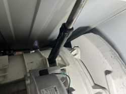 Widok wnętrza pralki Hotpoint, pokazujący amortyzator i elementy bębna.