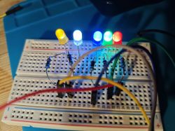 Five lit LEDs on a breadboard, displaying different colors.