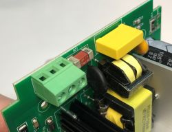 A section of a circuit board with electronic components, including a screw terminal, coil, and capacitor.