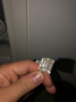 Wtyczka RJ-45 trzymana w dłoni.