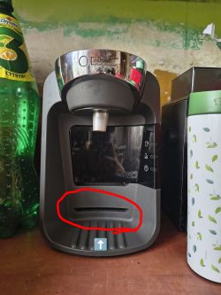Ekspres kapsułkowy na blacie; na dole zaznaczona na czerwono szczelina przy tacce ociekowej.