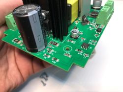 Zbliżenie na płytkę drukowaną z elementami elektronicznymi, w tym kondensatorami, rezystorami i złączami śrubowymi.