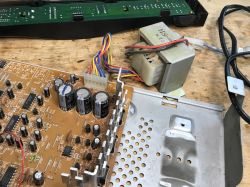 Płytka drukowana z komponentami elektronicznymi i transformator.