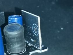 Close-up of an electronic board with blue capacitors and a chip.